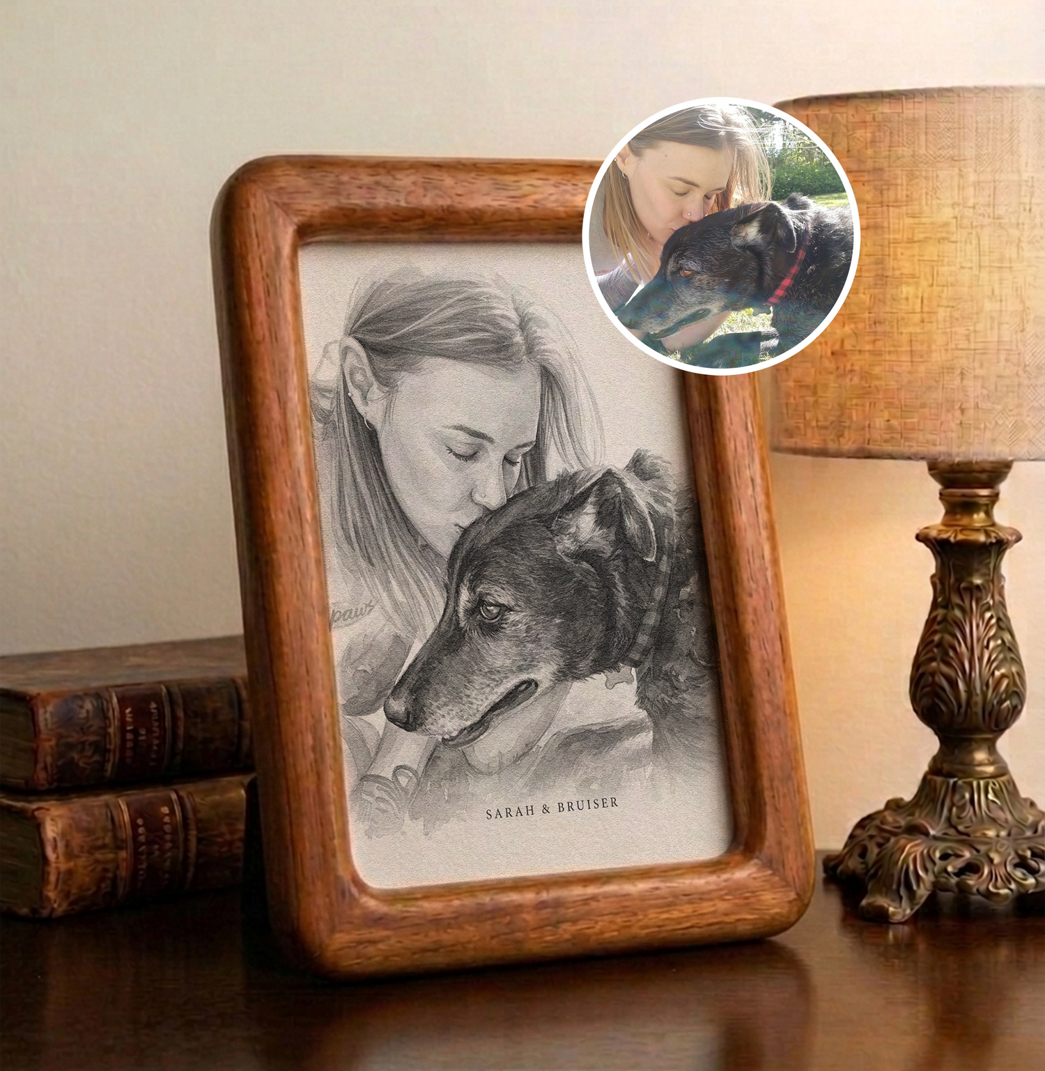 Custom watercolor portrait of a woman and her black dog in a wooden frame on a desk. The artwork shows a tender moment where the owner is kissing the dog’s head, featuring the names "Sarah & Bruiser" at the bottom.