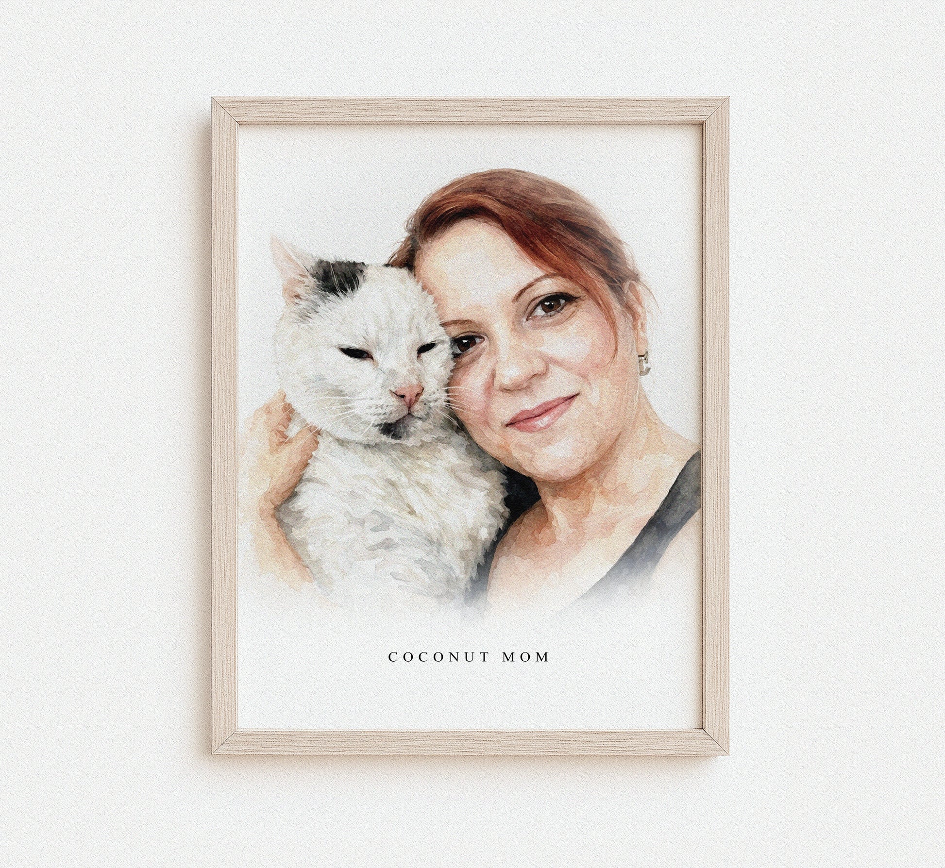 A framed watercolor-style portrait of a person holding their pet, displayed as wall art.